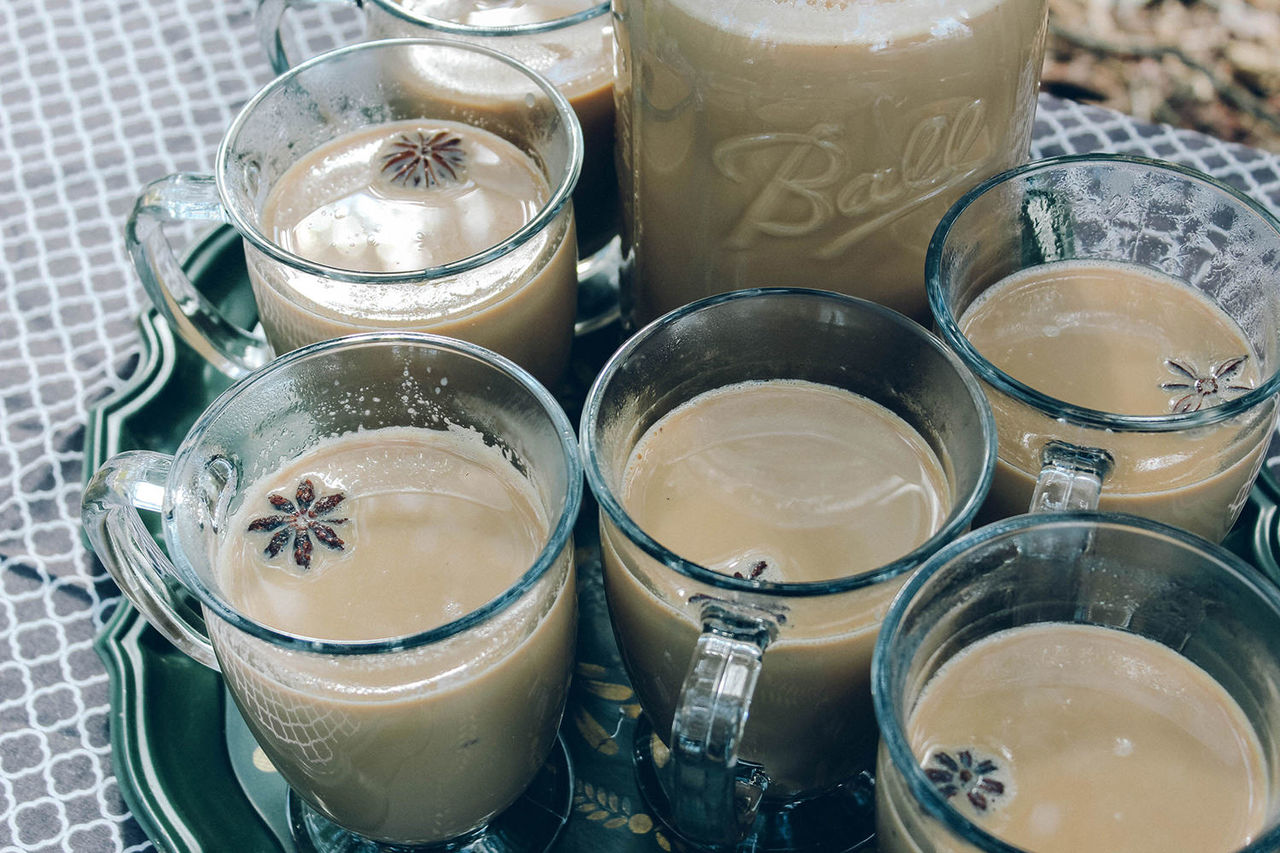 A close-up of chai ingredients in small glass mugs, showing spices.